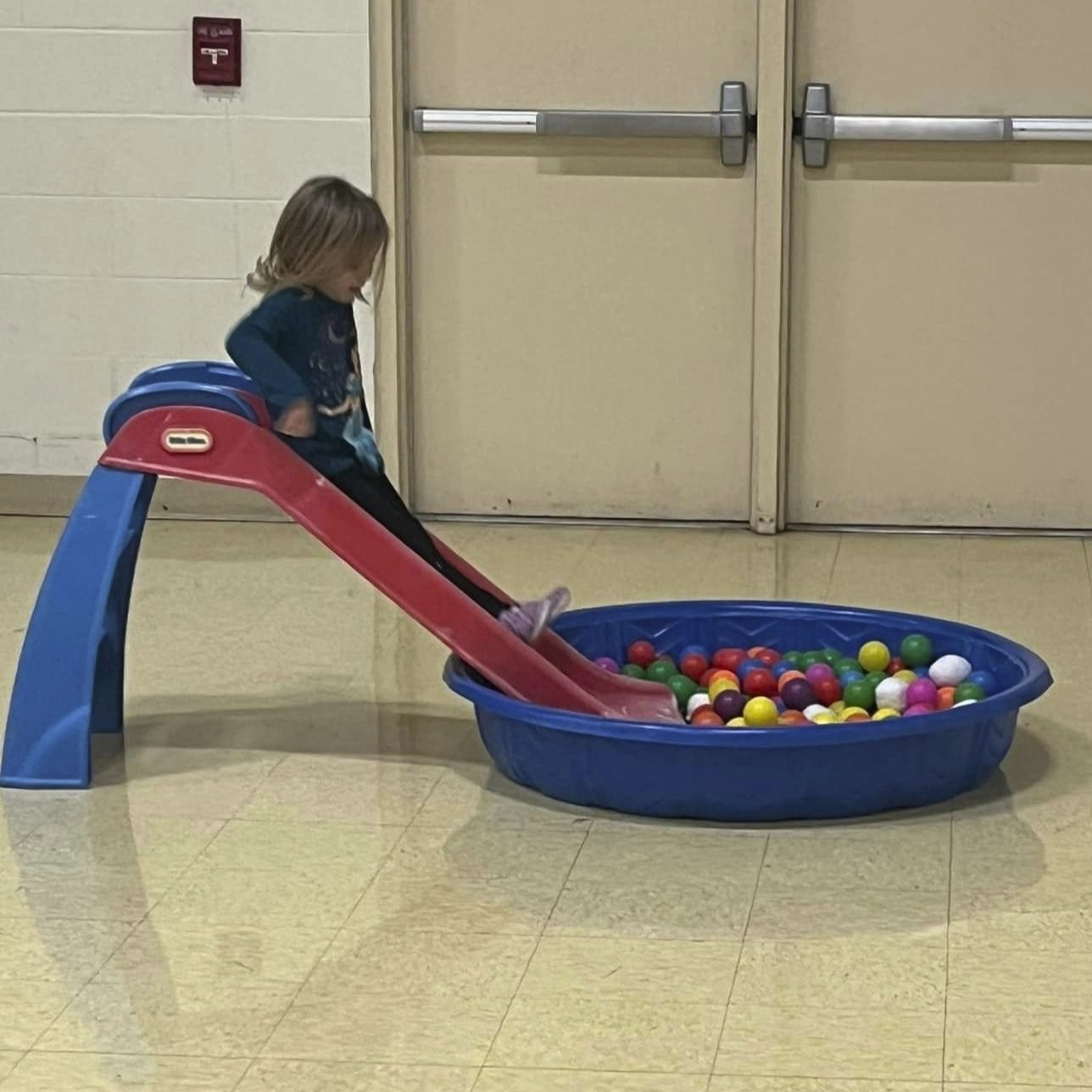 Toddler going down a slide into a ball pit at Toddler Open Gym